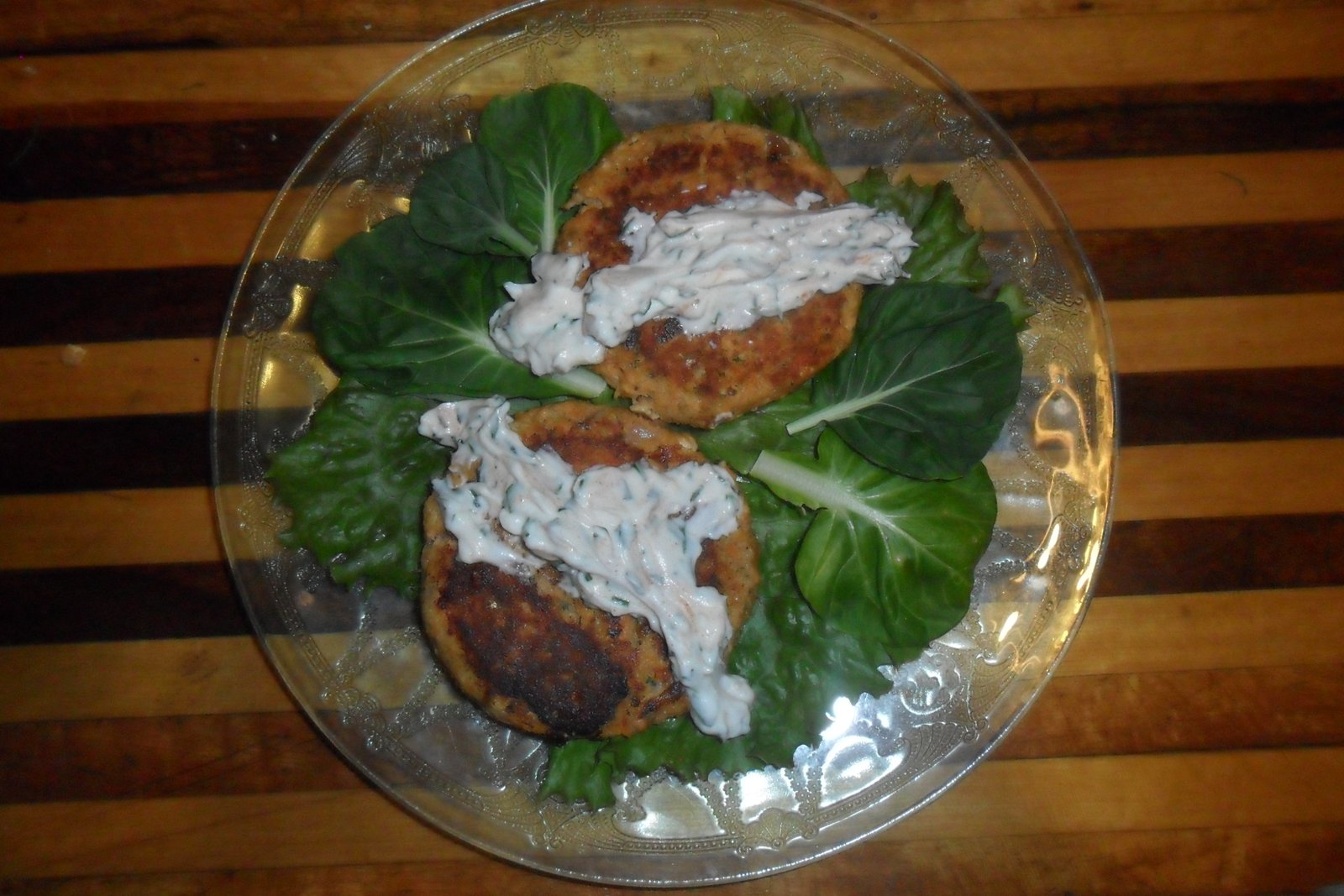 Salmon patties on fresh greens with yogurt sauce