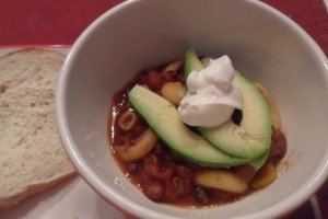 chili in bowl with avocado and sour cream topping