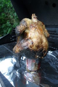 Chicken sitting on can on grill