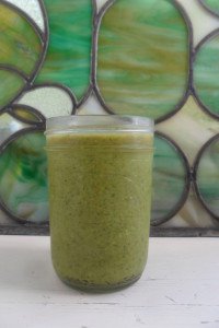 canning jar of basil pesto in front of stained glass window