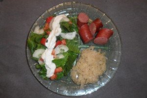 Divided plate with salad as the main course, sauerkraut, and kielbasa