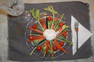 Celery, carrots, zucchini, brocolli, tomatoes all arranged in a giant wheel with dip in the center.