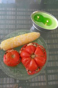 Baked Stuffed tomatoes on plate by citronella candle