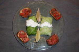 Cabbage rolls accented with lemon slices and cream on plate with bruschetta