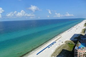 clear blue and emerald green water along a long, white sandy beach