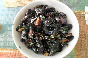 Cooked mussels in big white bowl on summer table