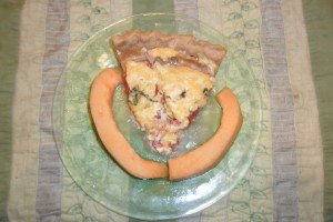 Slice of tomato pie on plate with cantaloupe