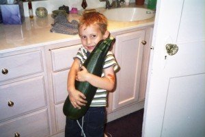 cute little fella grasping a zucchini half his size