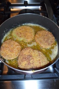 Breaded tomatoes browning in pan.