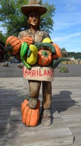 A cowboy carved in wood carrying a load of colorful vegetables