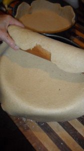 Placing dough over pan with rolling pin.