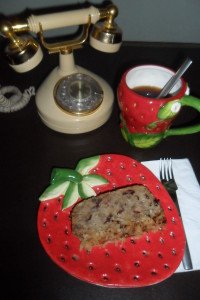 Apple bread on a strawberry plate with coffee and an old phone