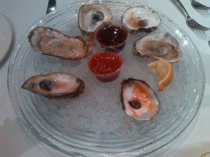 Plate of half-eaten oysters with lemon and sauces.