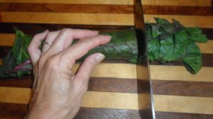 Slicing a roll of chard leaves