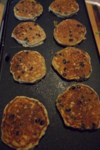 Blueberry pancakes browning on the griddle.