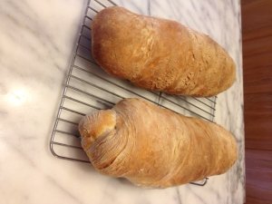 Two beautiful, long loaves of Tuscan bread on rack