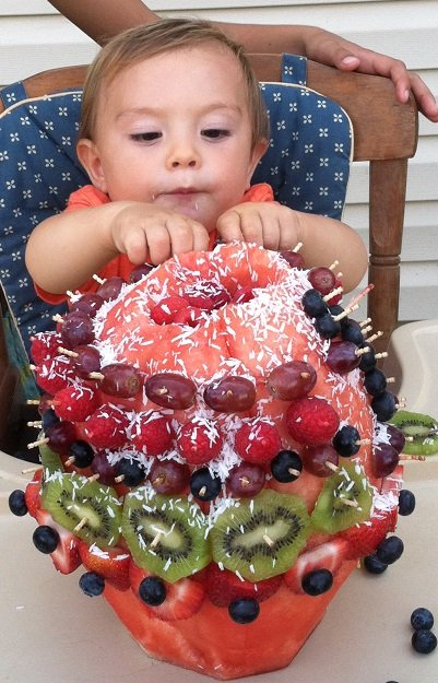 Adorable little kid digging into fruit cake