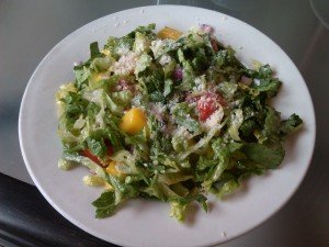 full plate of salad with a variety of toppings including mango pieces