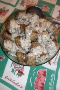 Huge bowl of meatballs and gravy on vintage tablecloth.