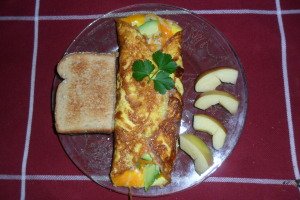 Serving parsley-garnished omelet with apple slices and toast.