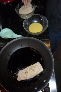 Dipping fish in breadcrumbs and frying.