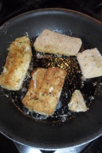 Fives pieces of fish browning in pan