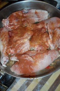 Paprika on raw chicken in pan.