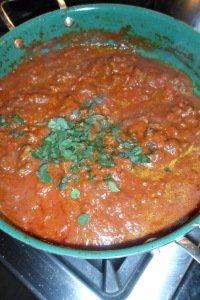 Adding the herbs to the tomatoes.