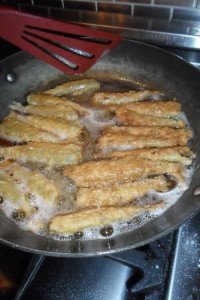 Frying breaded smelt.