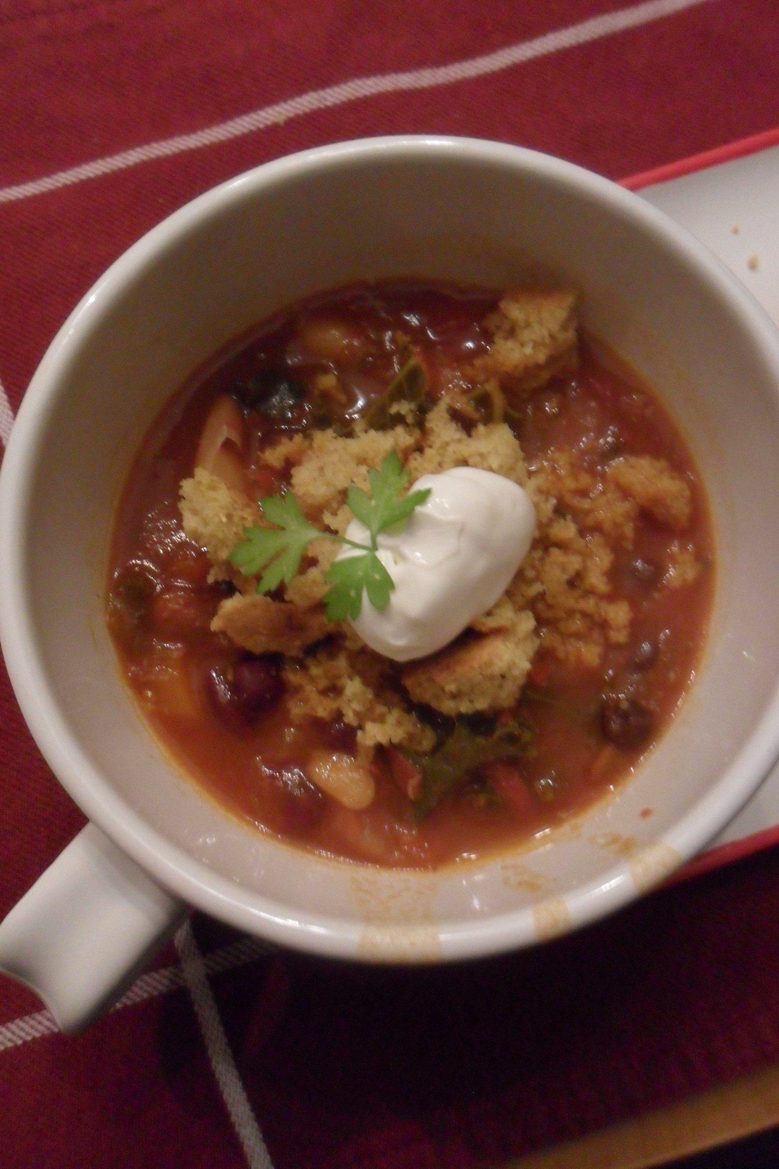 Serving chili in a mug with sour cream and parsley.