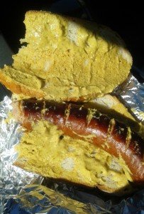 Grilled sausage on sourdough covered in mustard.