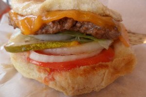 Juicy burger with sliced onion, pickles, lettuce, and tomato.