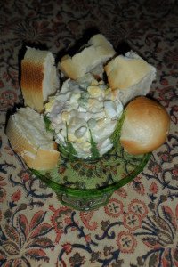 Serving Olivier Salad surrounded by baguette pieces.