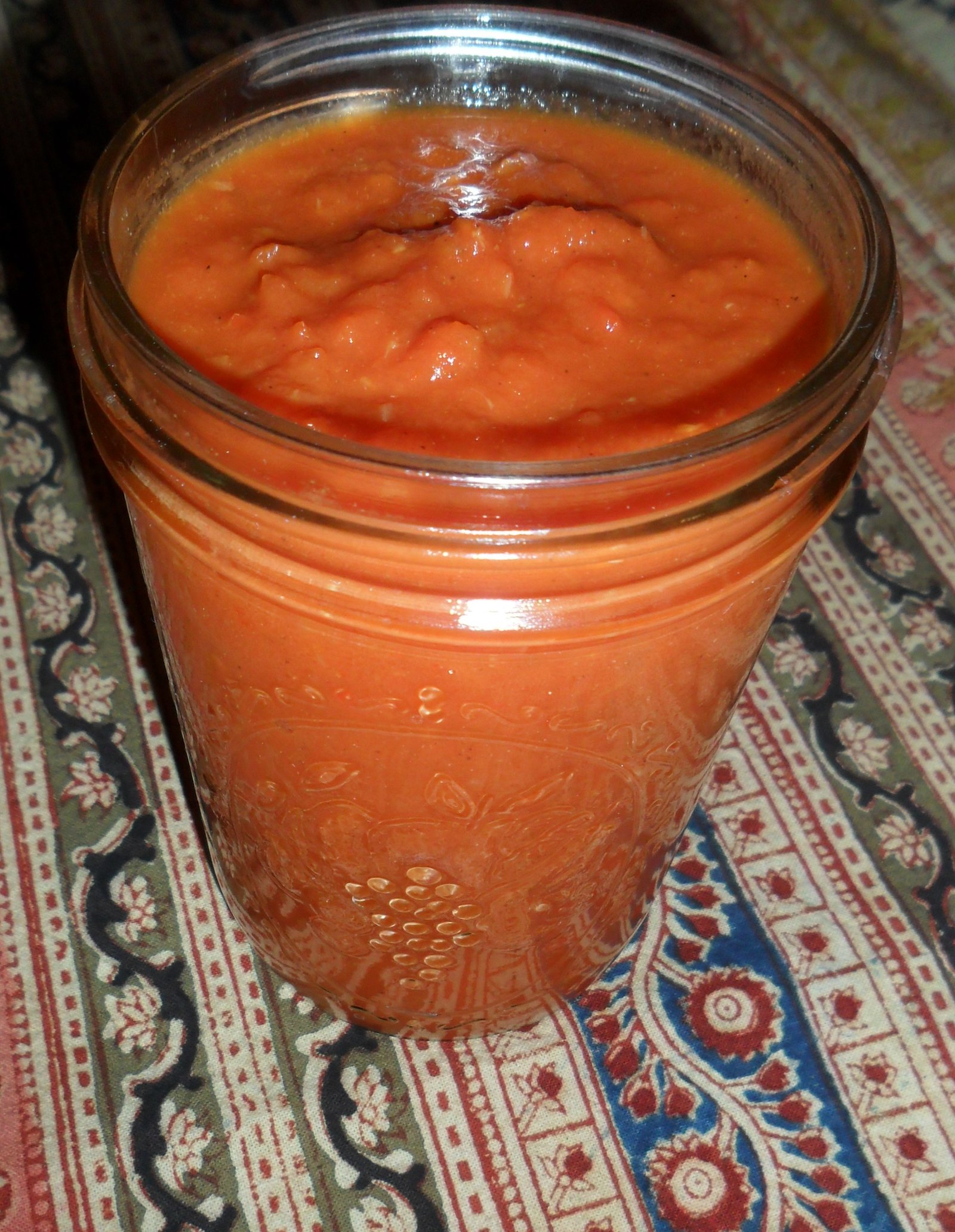 Fresh ketchup in canning jar on Indian cloth.