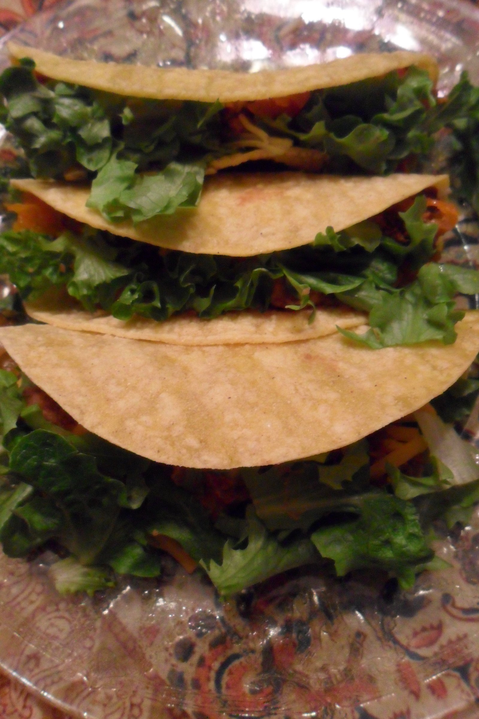 Serving three tacos brimming with lettuce.