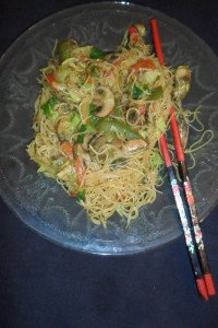 Serving Singapore Stir-Fry on clear plate with chopsticks.