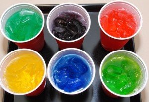 Six plastic cups with unnaturally dyed drinks.