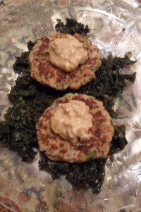 Serving salmon patties on bed of kale.