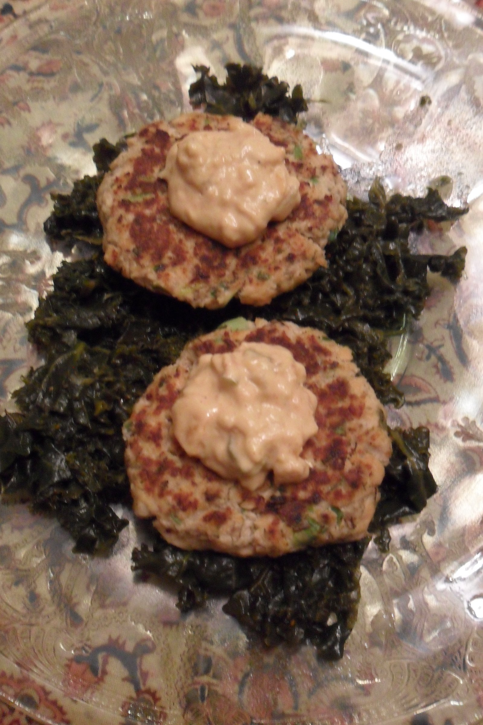 Serving salmon patties on bed of kale.