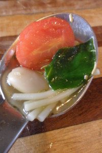 Spinach, tomato, bean, and noodles on a spoon.