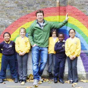 Jamie standing with five school kids in front of a rainbow painting.